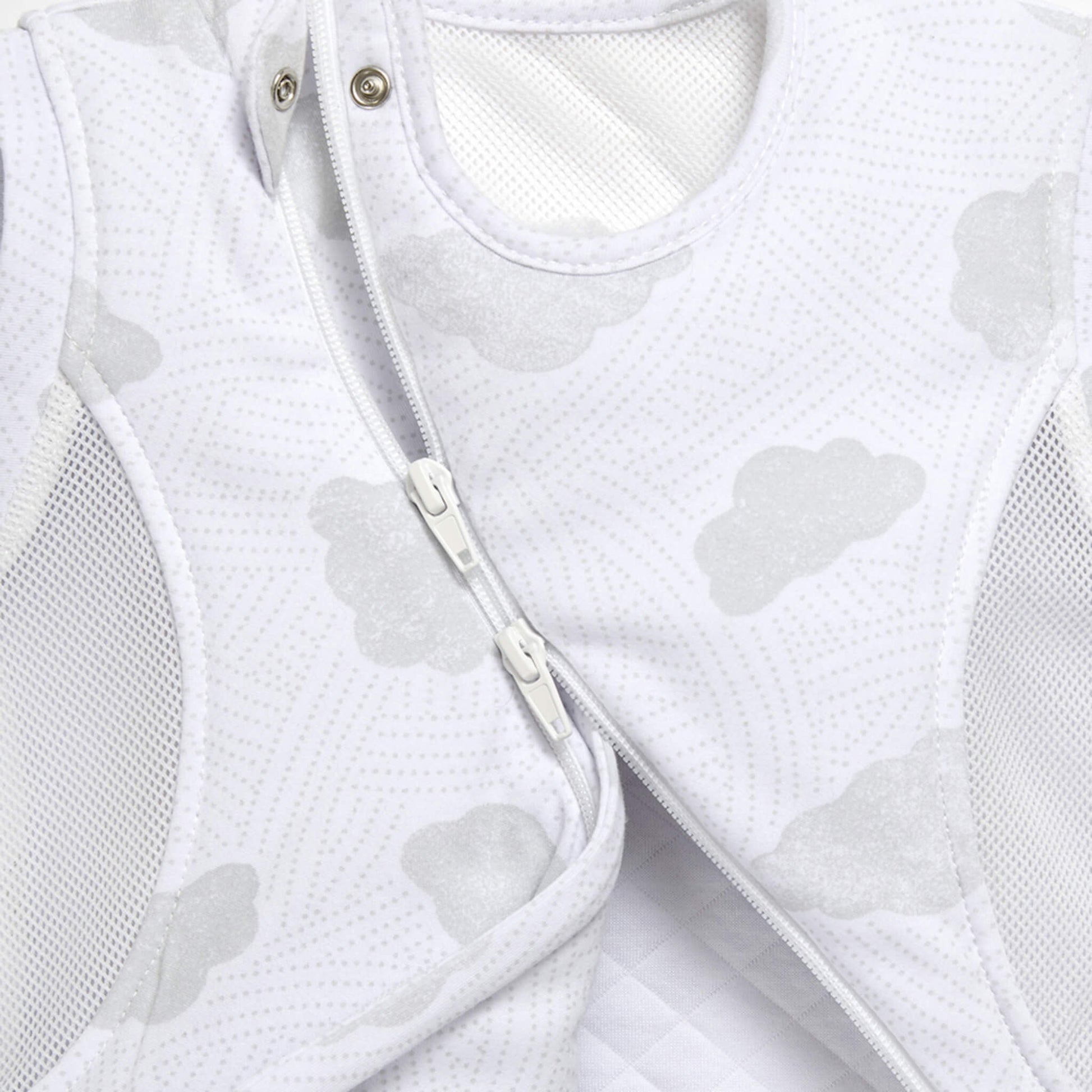 A detailed view of two front zips on a sleep bag, showing how the curved fastening opens across the cloud-patterned fabric.