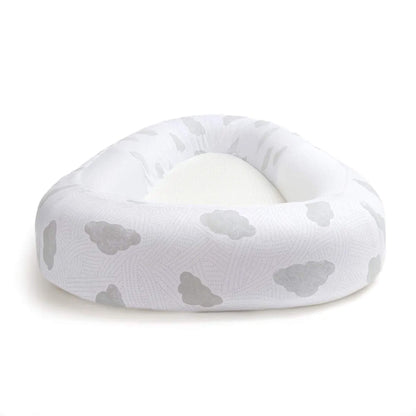 A baby bed with soft cloud-print fabric and raised cushioned sides, shown from a low front angle.