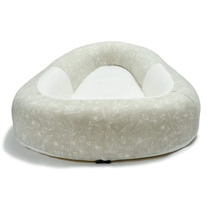 A side view of a baby bed with raised, structured sides and a firm, flat mesh sleeping surface.