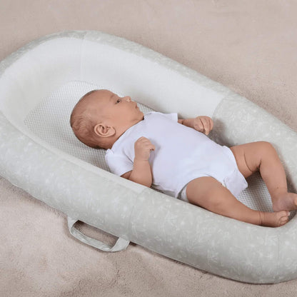 A baby lying comfortably in a baby bed, showing the depth of the sides and the flat, supportive mattress surface.