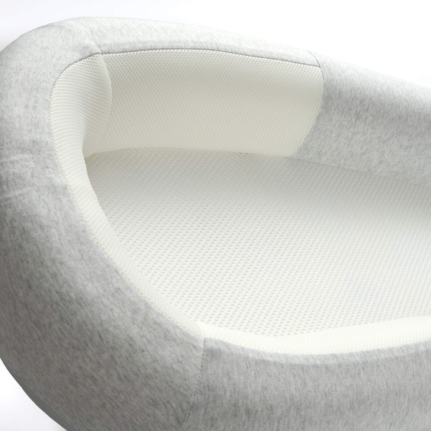 A close-up view of a breathable mesh mattress and softly structured side panel inside a grey baby bed.