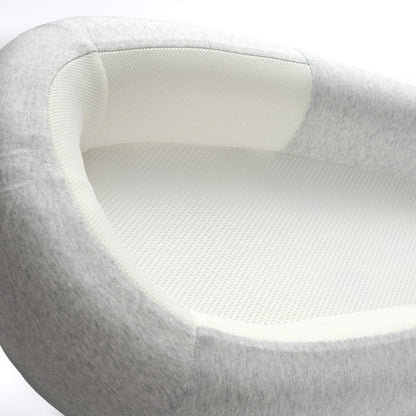 A close-up view of a breathable mesh mattress and softly structured side panel inside a grey baby bed.