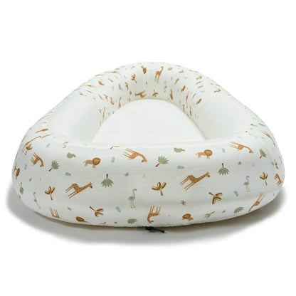 A baby bed shown from the front, featuring raised structured sides, a firm flat inner surface, and a safari animal print outer.