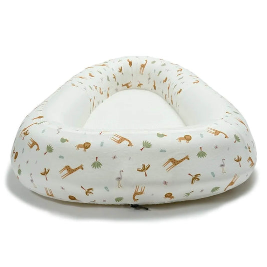 A baby bed shown from the front, featuring raised structured sides, a firm flat inner surface, and a safari animal print outer.