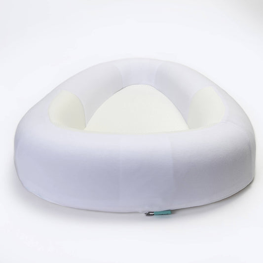 A baby bed with softly structured sides and a breathable mesh base, shown from a low angle to highlight the open, cushioned shape.