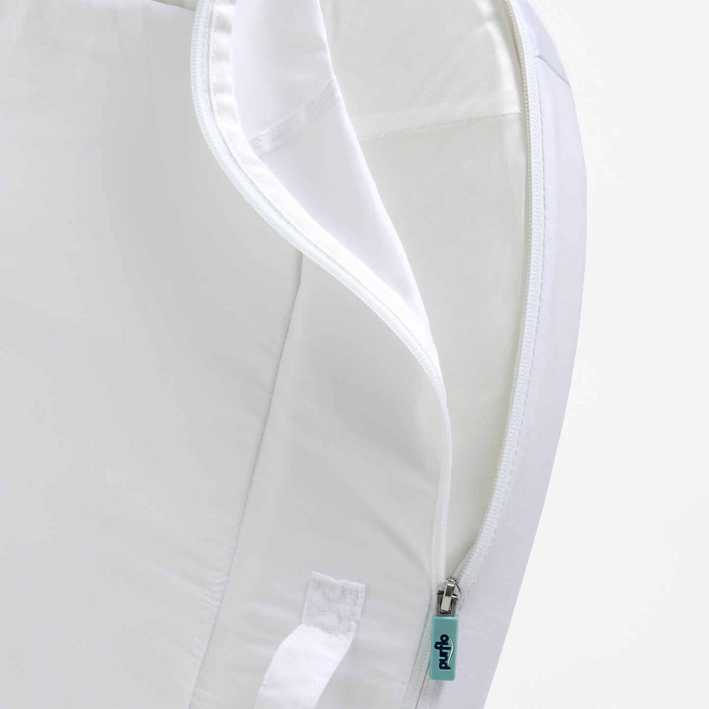 A close-up of a removable fabric cover being unzipped from a baby bed, showing stitched seams and a wipe-clean inner surface.