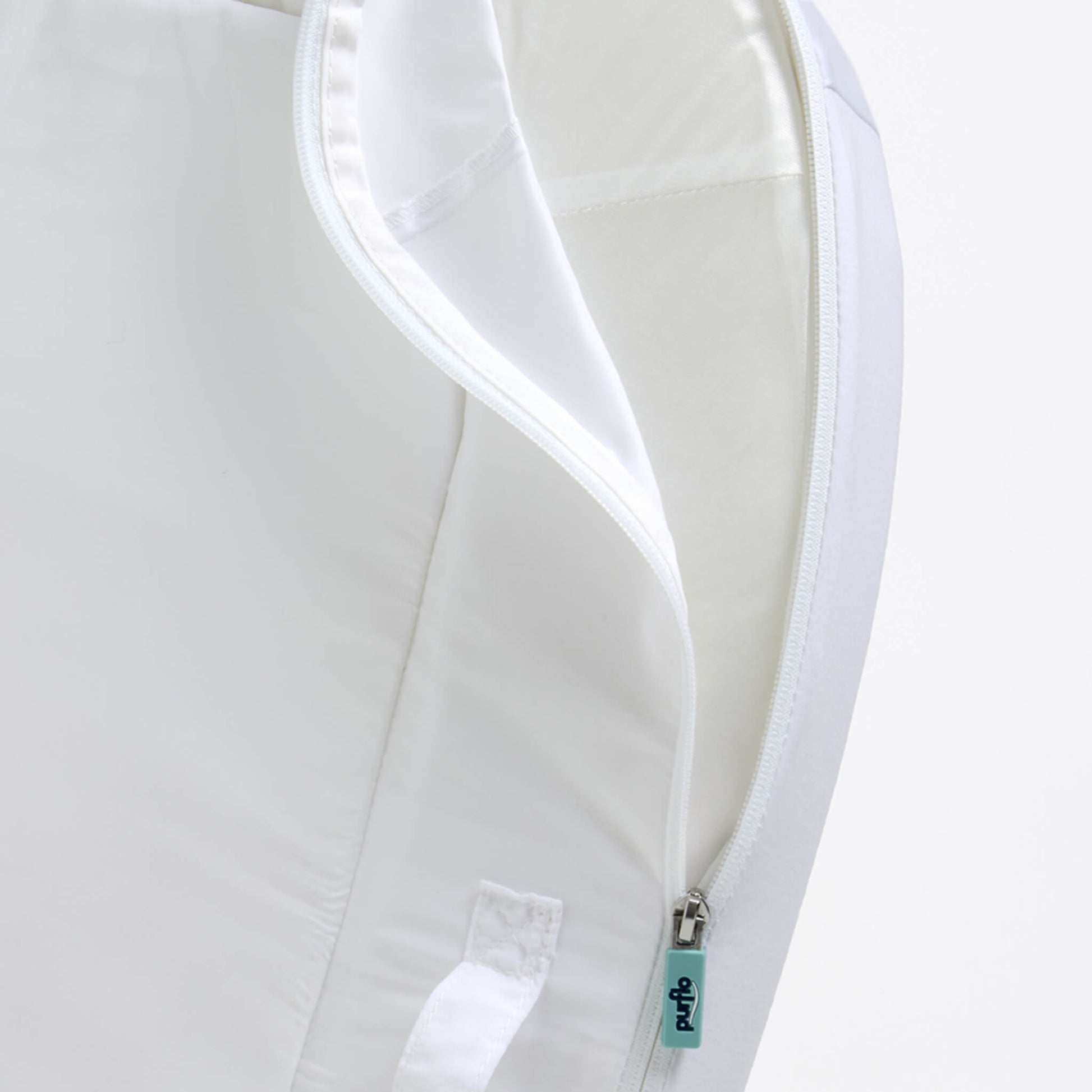 A close-up of a removable fabric cover being unzipped from a baby bed, showing stitched seams and a wipe-clean inner surface.