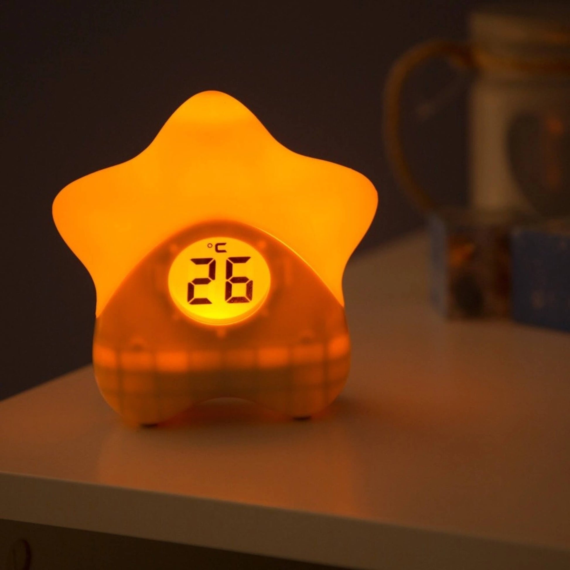 Star-shaped night light glowing warm amber with digital temperature display reading 26°C.