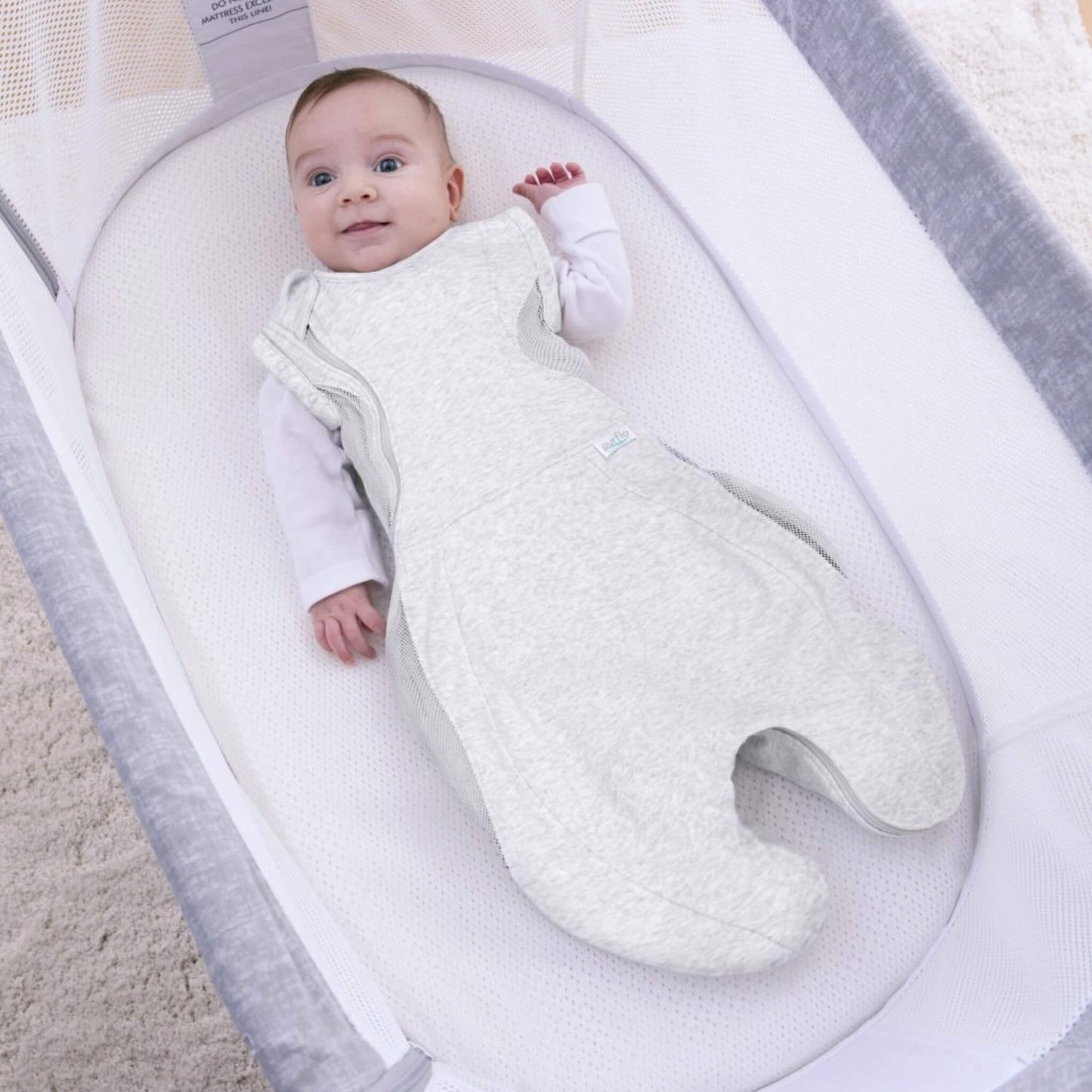 A baby lying awake in a grey swaddle sleep bag with arms out, showing the option to transition from swaddling as baby grows.