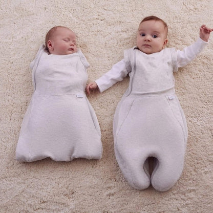 Two babies side by side on a soft surface, one swaddled with arms in and one with arms out, showing different sleep stages.