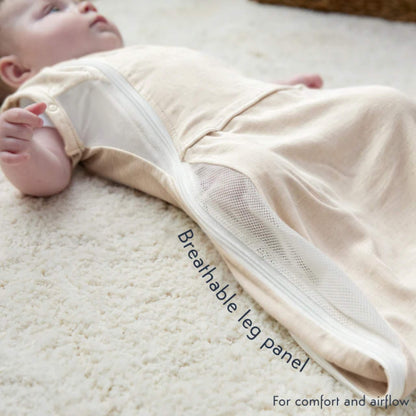 A baby lying comfortably in the Summer Sand swaddle bag with the breathable mesh side panel visible.