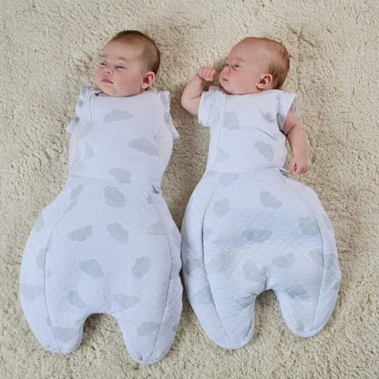 Two babies resting next to each other on a textured rug, wearing cloud-patterned sleep bags, showing one set in arms-in swaddle mode and the other configured with arms out.