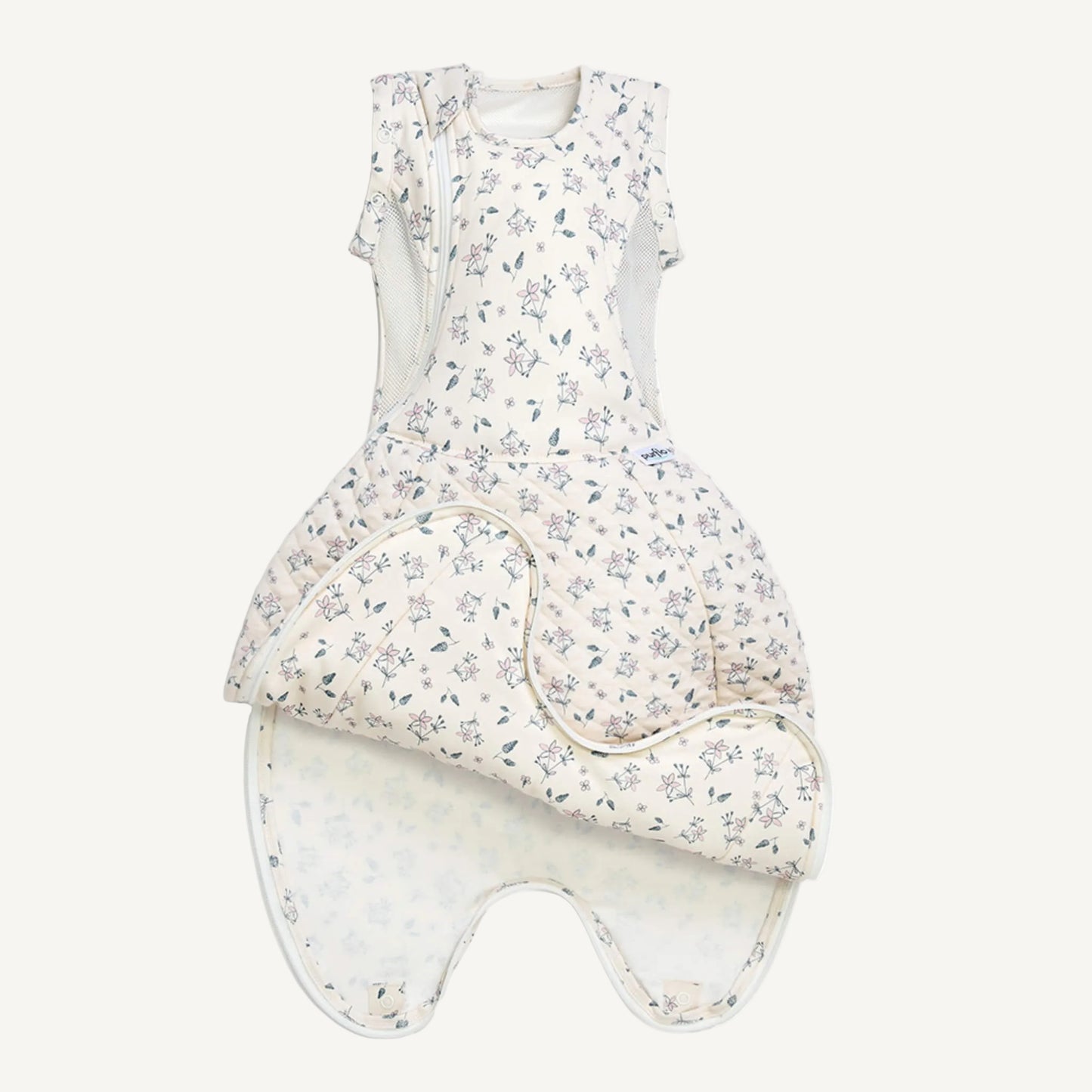 A swaddle to sleep bag laid flat with the lower section opened to show the extendable length and popper fastenings for growth.
