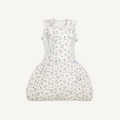 A swaddle to sleep bag laid flat with the lower section fully closed, showing the quilted fabric and curved hip-healthy shape.