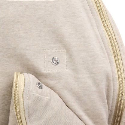A close-up of a press stud fastening on a beige baby sleep bag.