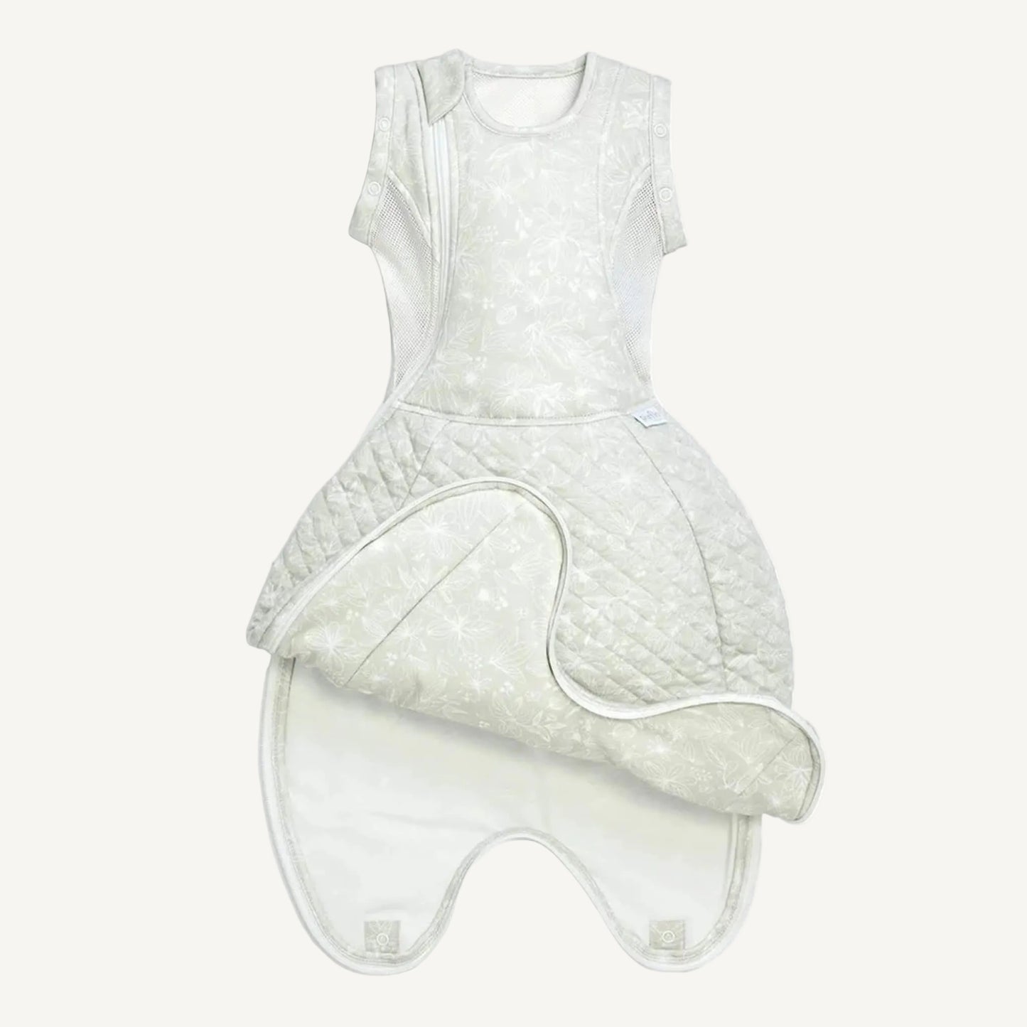 A swaddle sleep bag laid flat with a lower flap opened to show the extendable length panel and popper fastenings at the base.