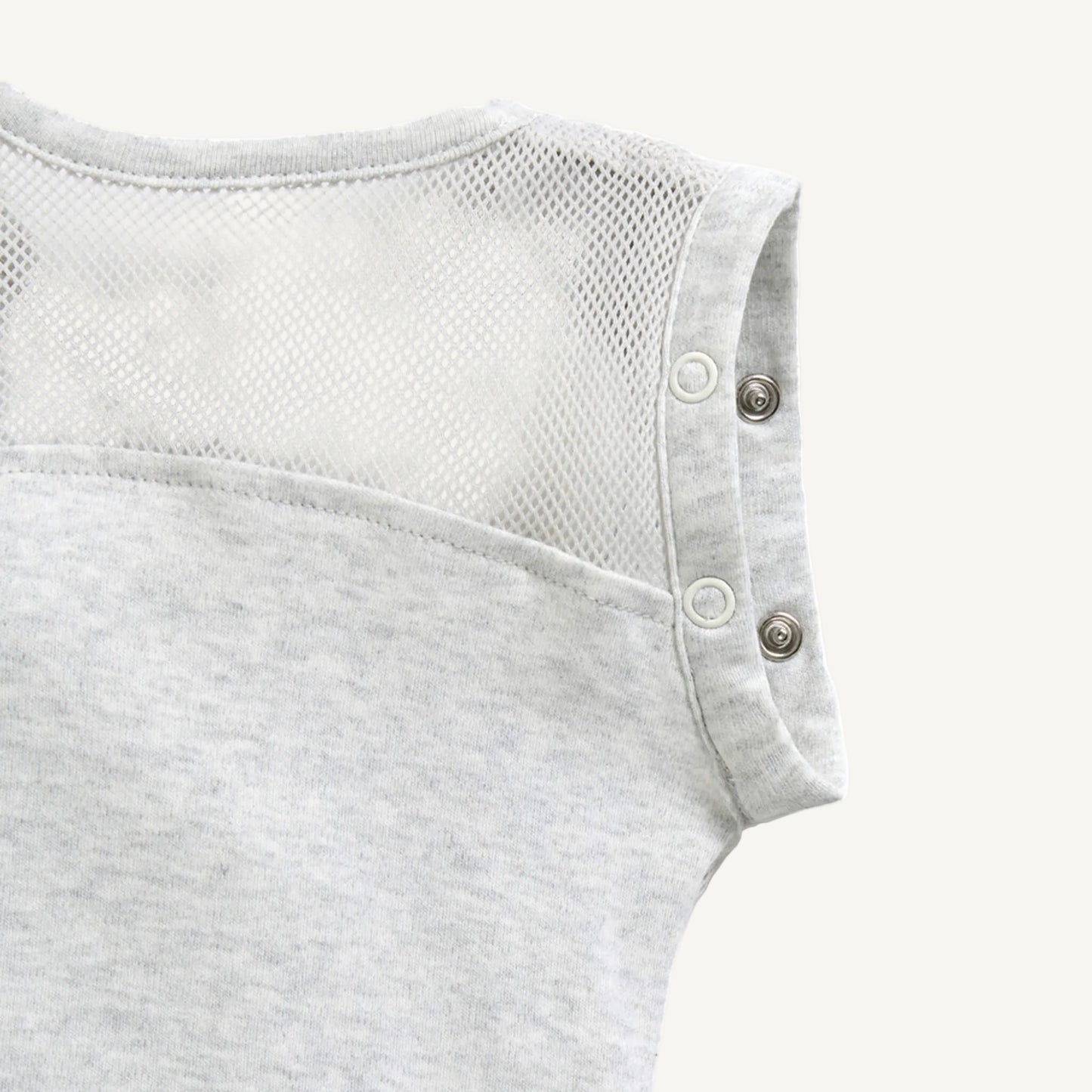 A close-up of breathable mesh fabric across the upper back area with popper fastenings at the shoulder seams.