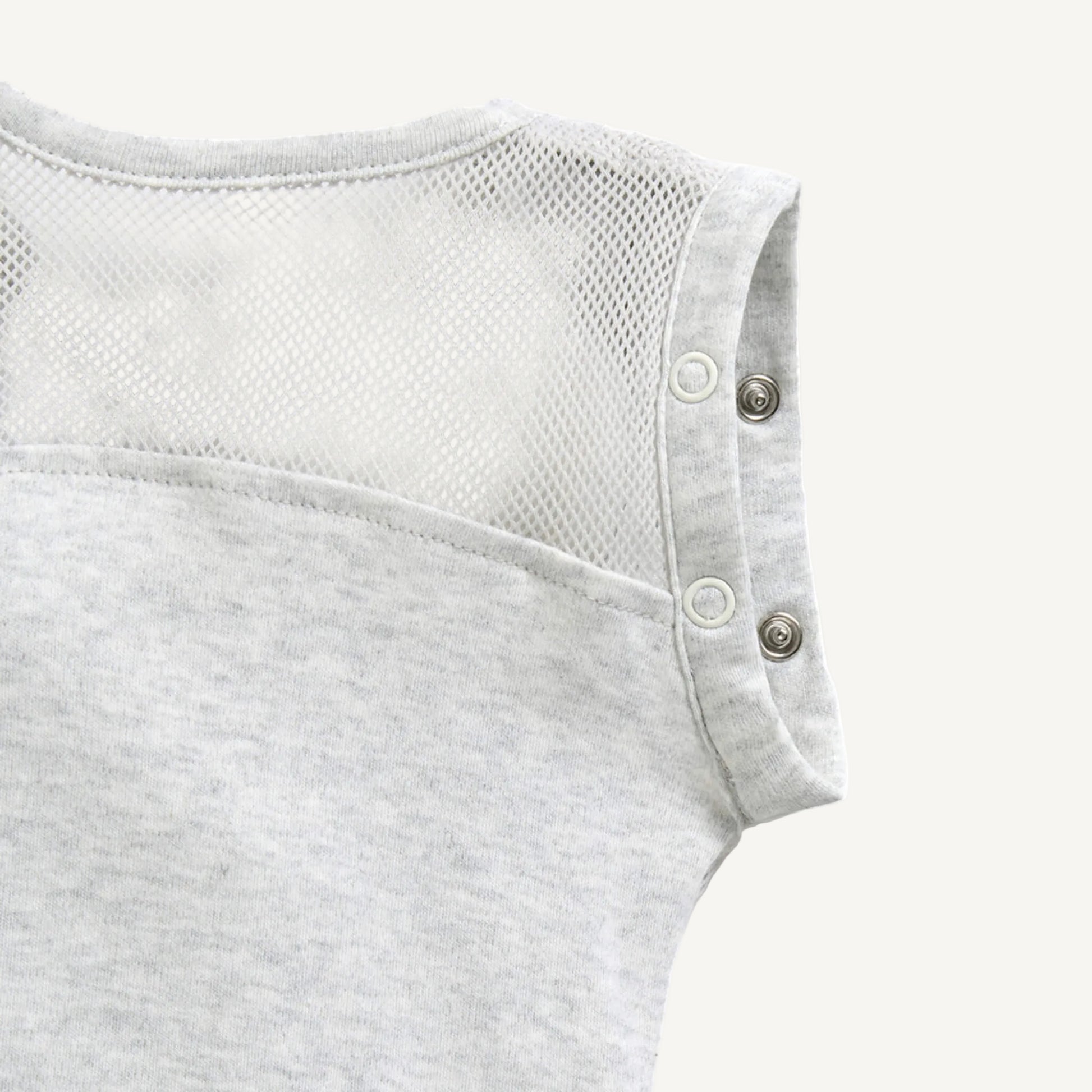 A close-up of breathable mesh fabric across the upper back area with popper fastenings at the shoulder seams.