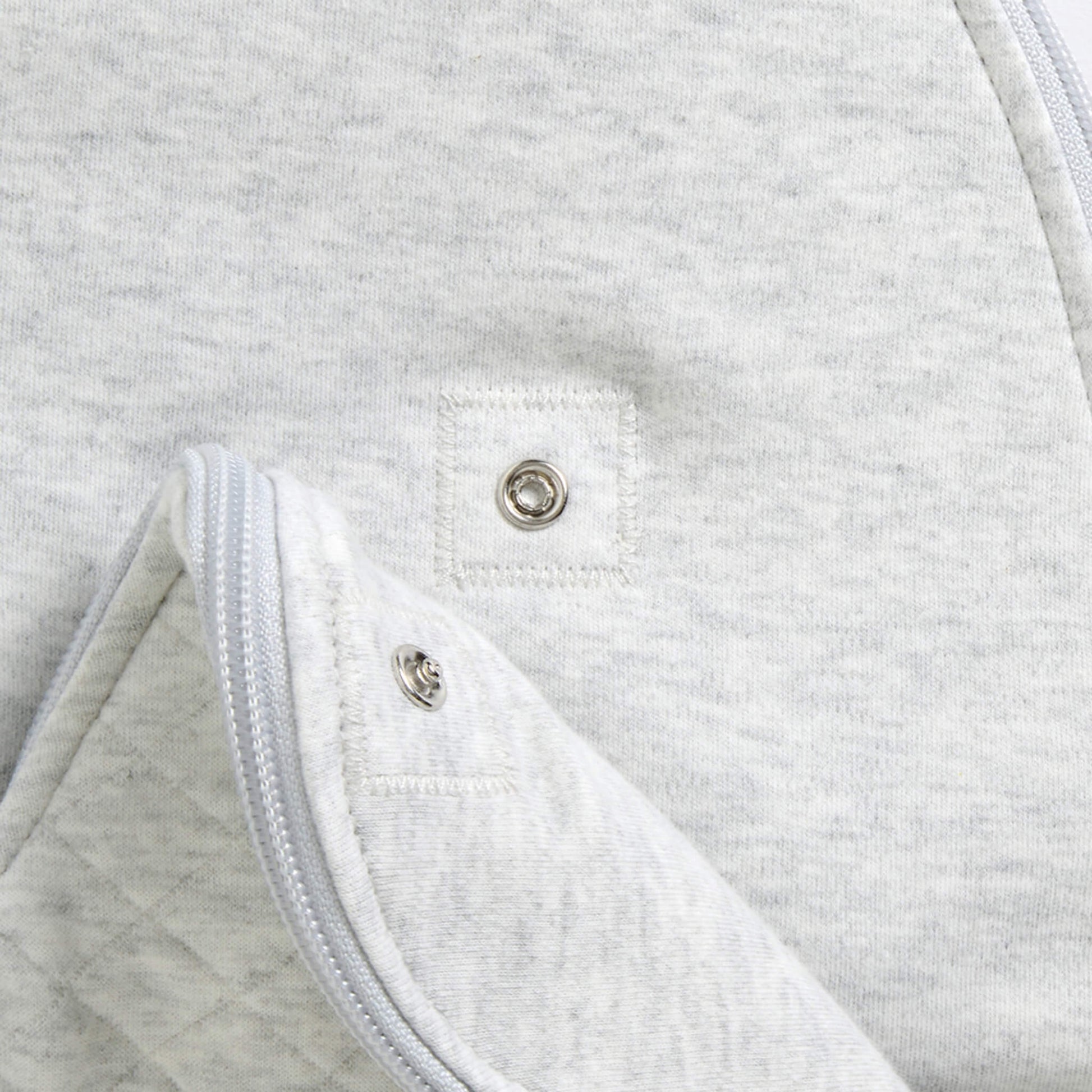 A close-up of the lower section showing quilted padding and internal poppers that allow the sleep bag length to be adjusted as a baby grows.