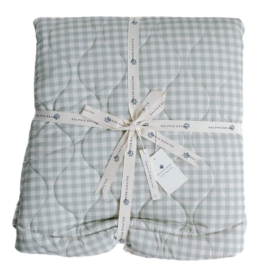 Ralphie Bear quilted playmat in sage green gingham, softly padded and folded with branded ribbon, showing stitched quilting detail and cushioned design.