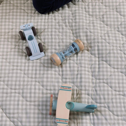 Wooden toy car, rattle and small plane placed on a soft quilted gingham play mat, showing texture and stitched pattern in detail.