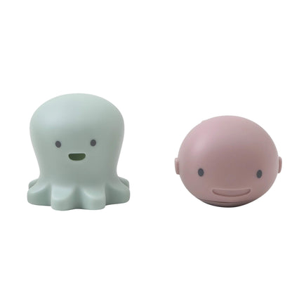A set of Shnuggle Bath Buddies featuring a mint octopus toy and a pink whale toy with smiling faces, designed for interactive baby bath time fun.
