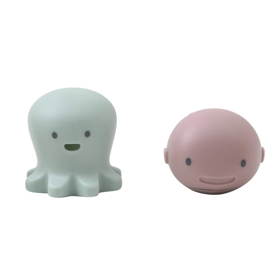 A set of Shnuggle Bath Buddies featuring a mint octopus toy and a pink whale toy with smiling faces, designed for interactive baby bath time fun.