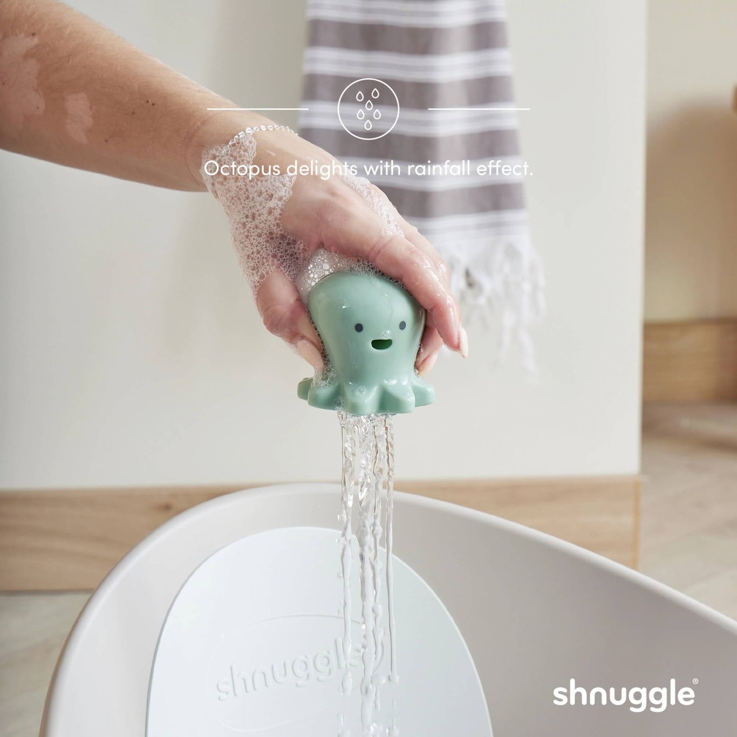 A mint green octopus bath toy held in an adult hand above a bath, with water pouring evenly through multiple holes.