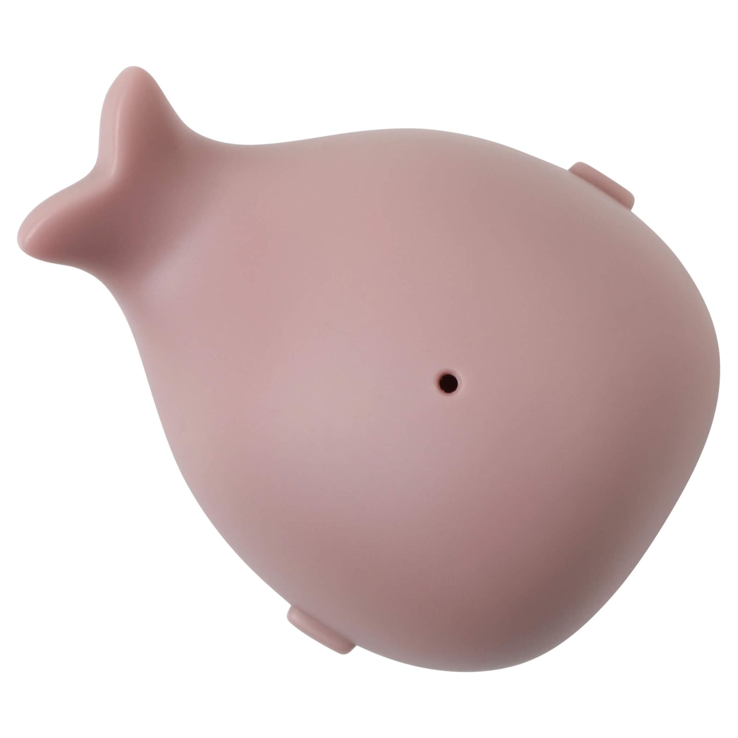 A pale pink whale-shaped bath toy lying on its back, showing a small water hole on the underside near the tail.