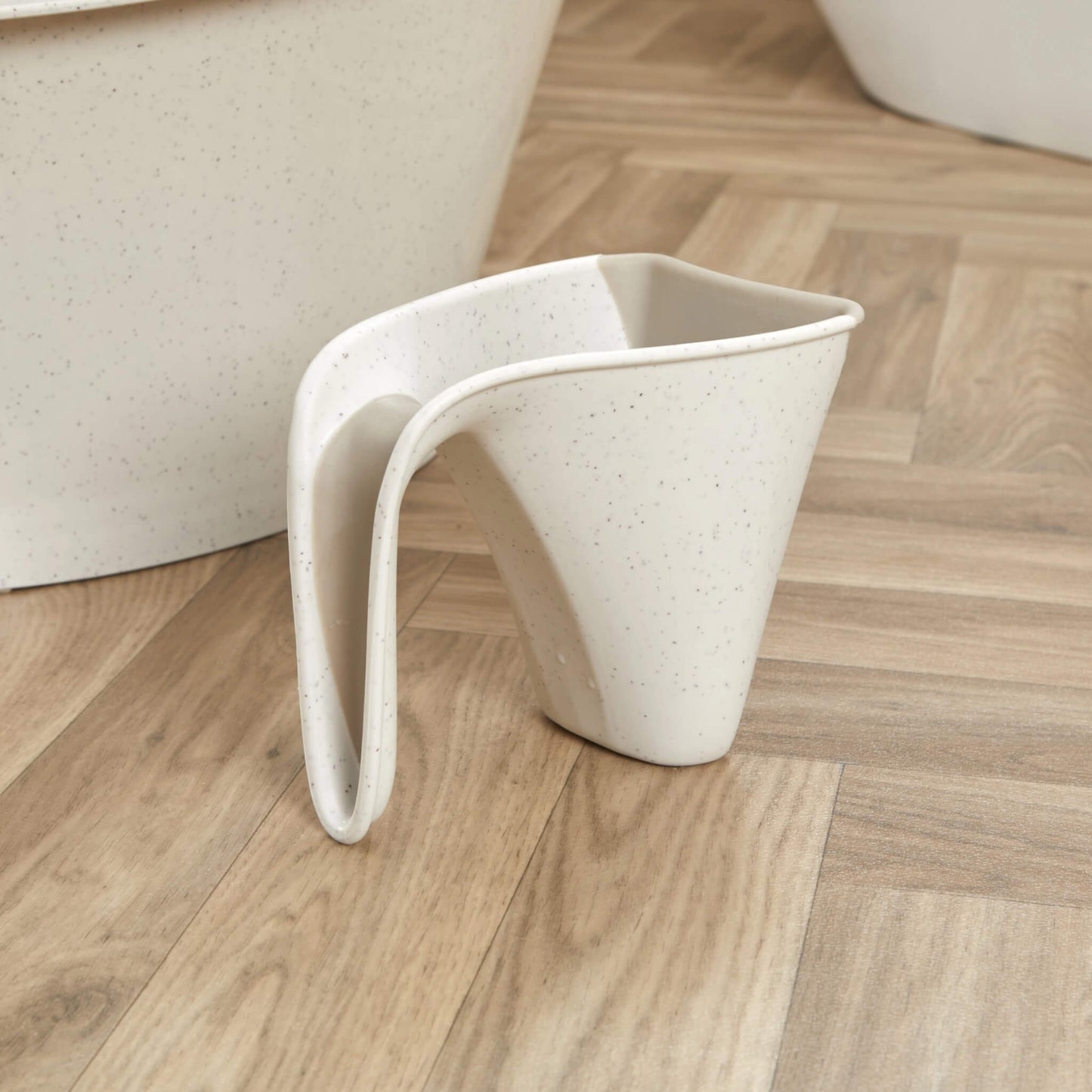 Cream jug placed on a wooden floor beside a matching baby bath, showing its compact size.
