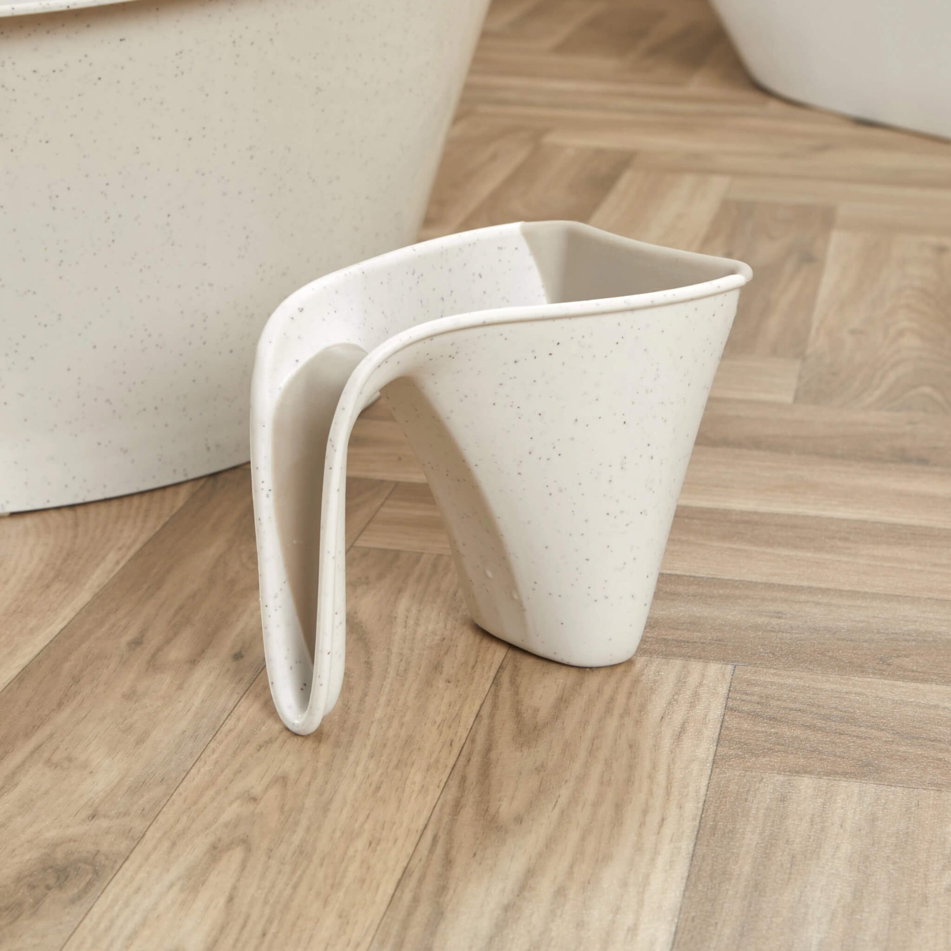 Cream jug placed on a wooden floor beside a matching baby bath, showing its compact size.