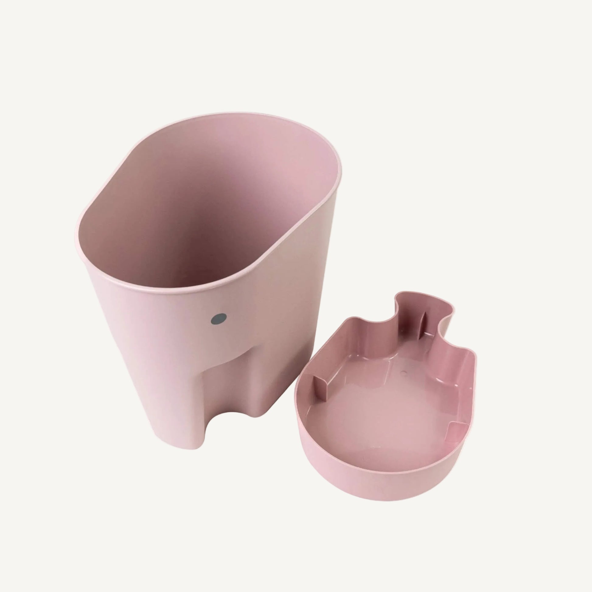 An elephant-shaped bath toy drying caddy in blush pink shown beside a matching drip tray, illustrating how excess water is collected while toys air dry.