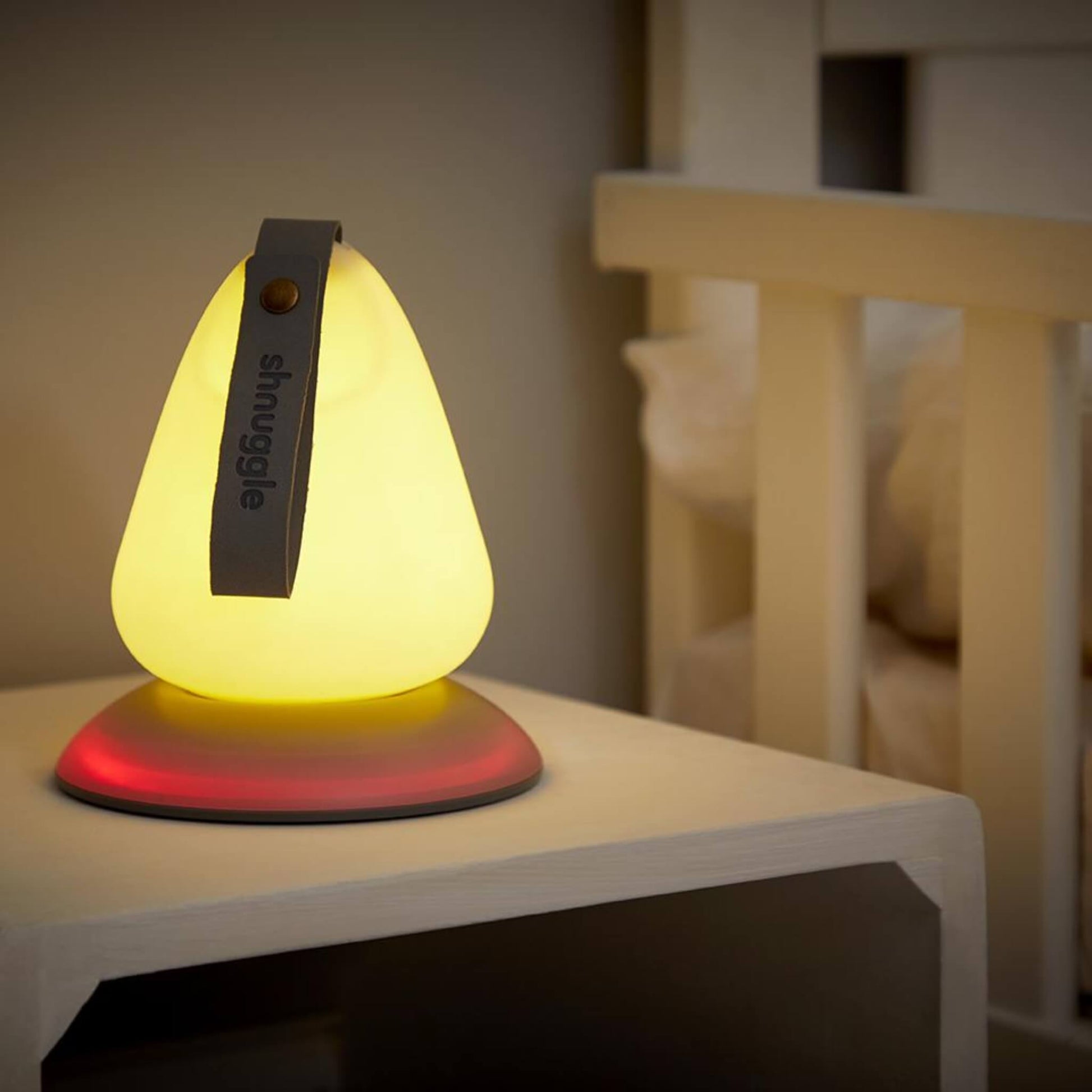 Nightlight glowing yellow with a red base light in a dark nursery setting.