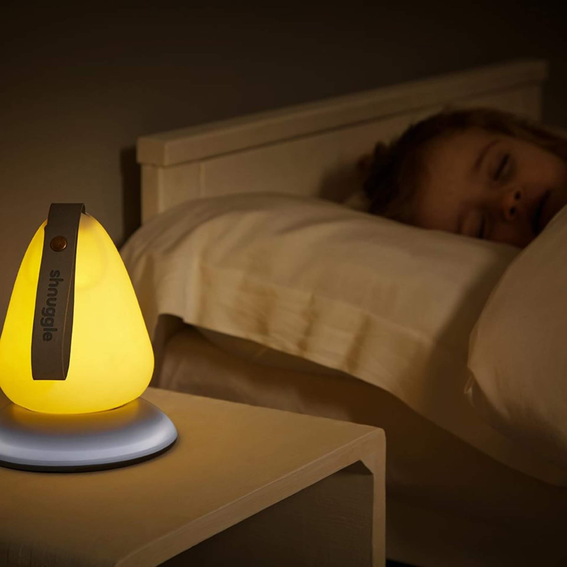 Nightlight glowing beside a sleeping child, placed on a bedside table close to the pillow.