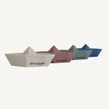 A row of four bath boats in muted neutral colours, each shaped with a raised sail and flat base.