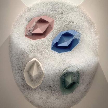 Four bath boats floating in a bubbly bath, viewed from above.