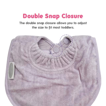 A side view of a baby dribble bib, showing the curved towelling front, stitched binding around the edge, and a small woven brand label sewn into the seam.