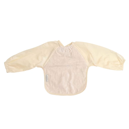 Silly Billyz Towel Long Sleeve Bib in cream, shown laid flat with an absorbent cotton towelling front, full-length water-resistant sleeves with elasticated cuffs, a gathered neckline, and a back snap closure.
