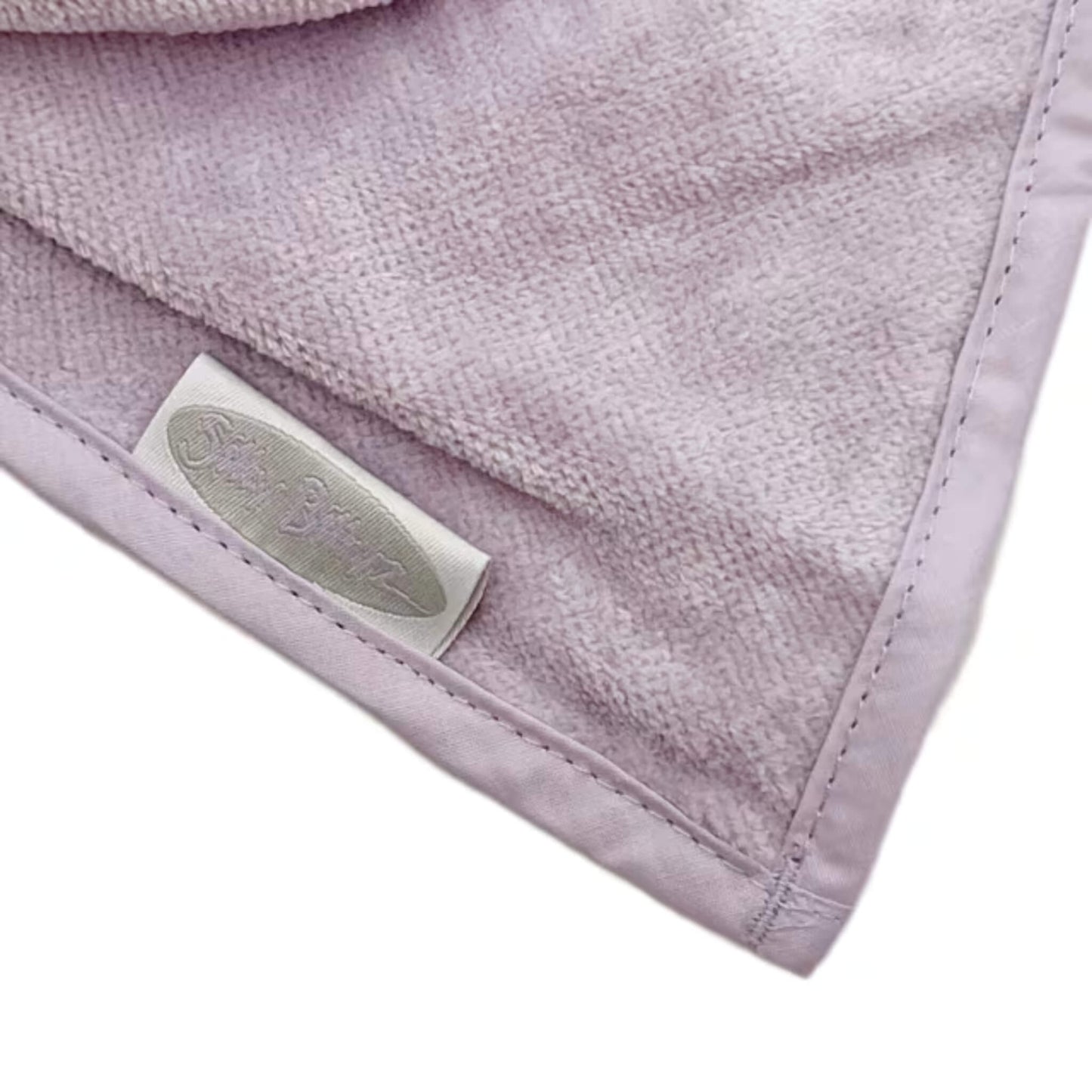 Detail view of soft velour towelling fabric on a lavender bandana bib, highlighting texture and stitched binding along the edge.