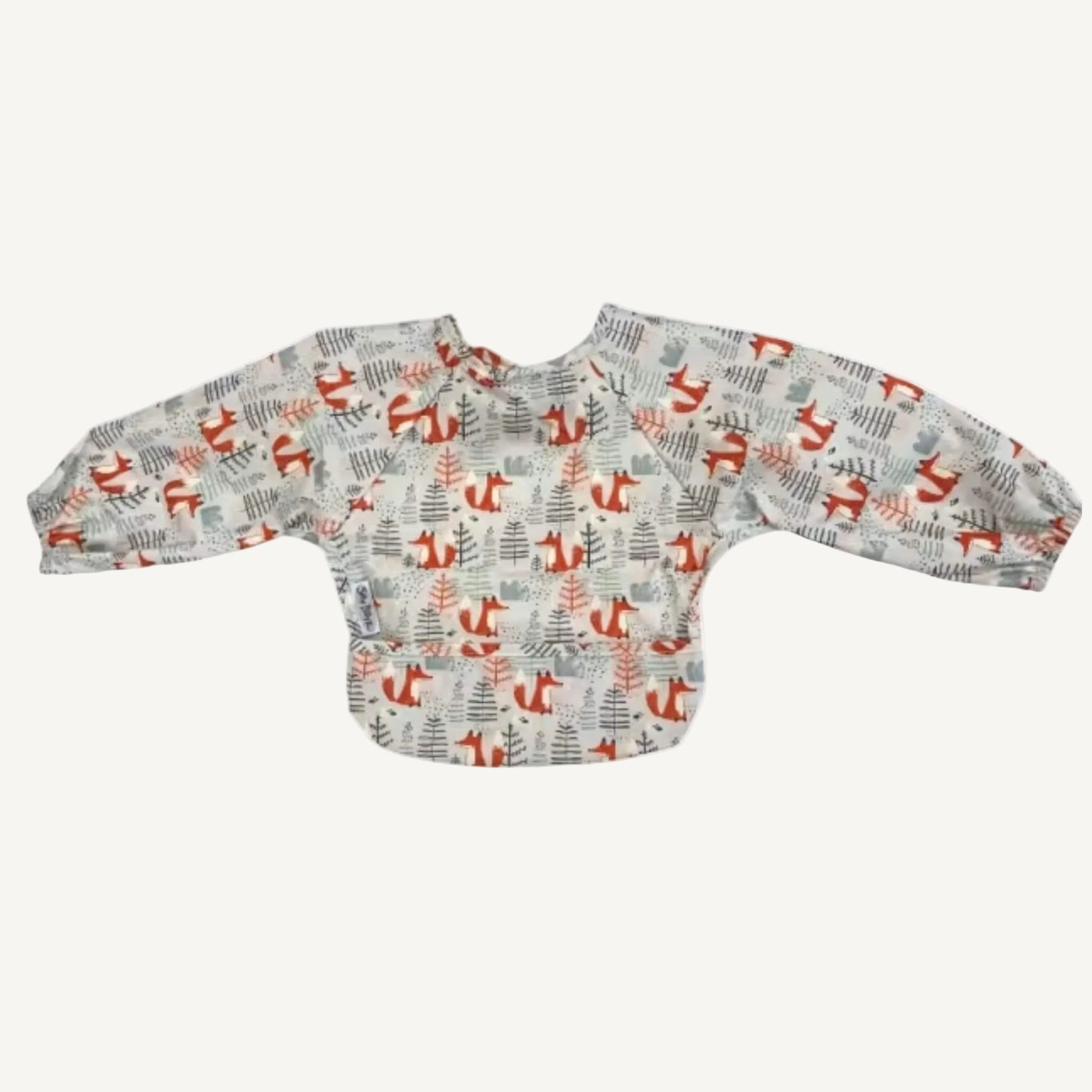 A long-sleeve bib in an illustrated fox and woodland pattern shown laid flat from the back, with gathered cuffs and a smooth wipe-clean finish.