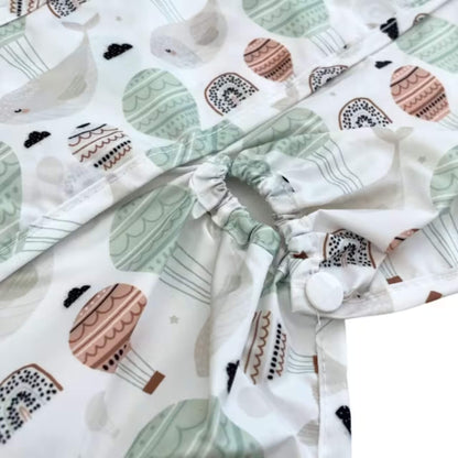 Close-up of the highchair attachment opening with elasticated edge and popper fastening, showing how the bib secures around the chair.