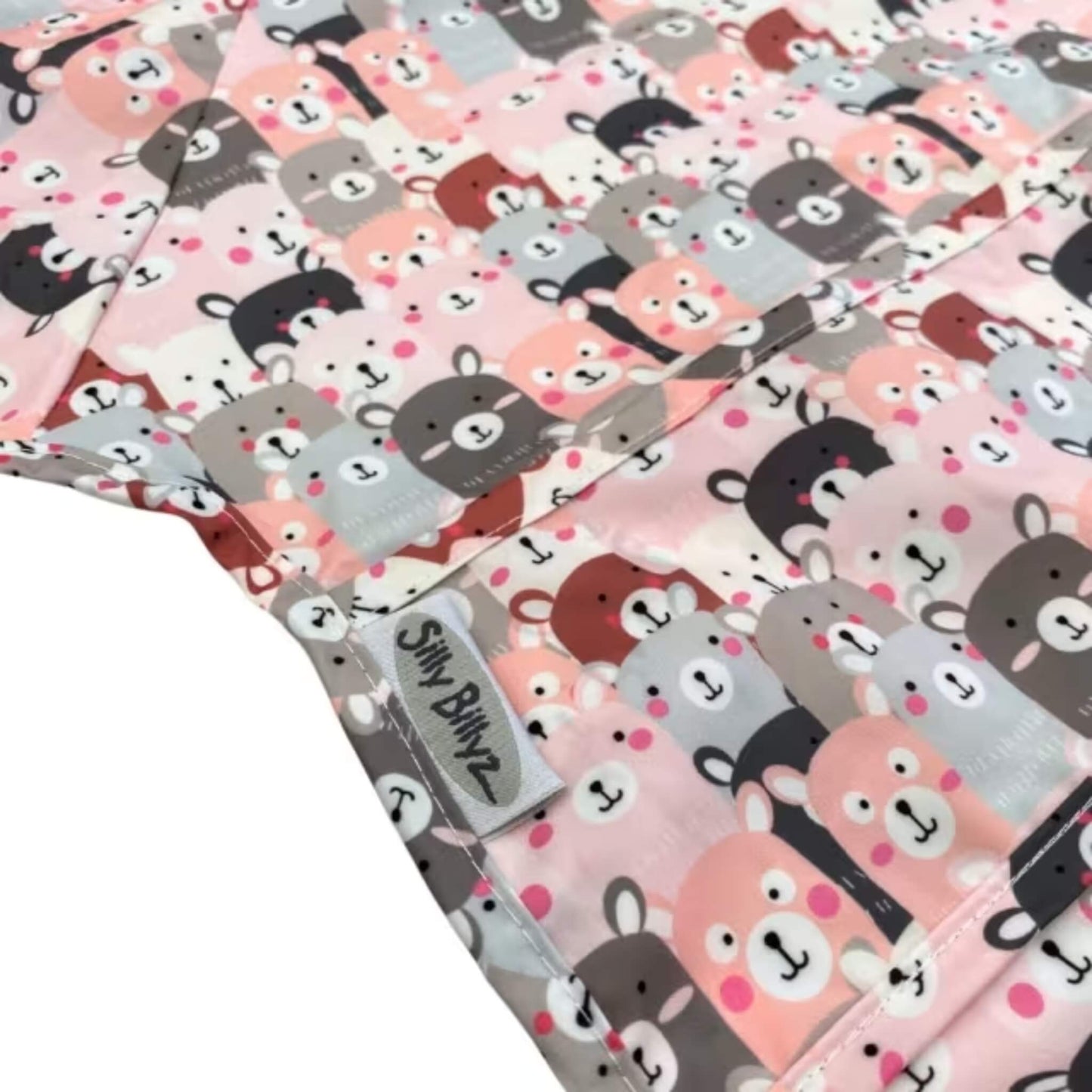 Close-up of wipe-clean fabric baby bib showing a repeating Peekaboo animal print in soft pink, grey, cream, and muted brown tones, with stitched seams visible across the surface.