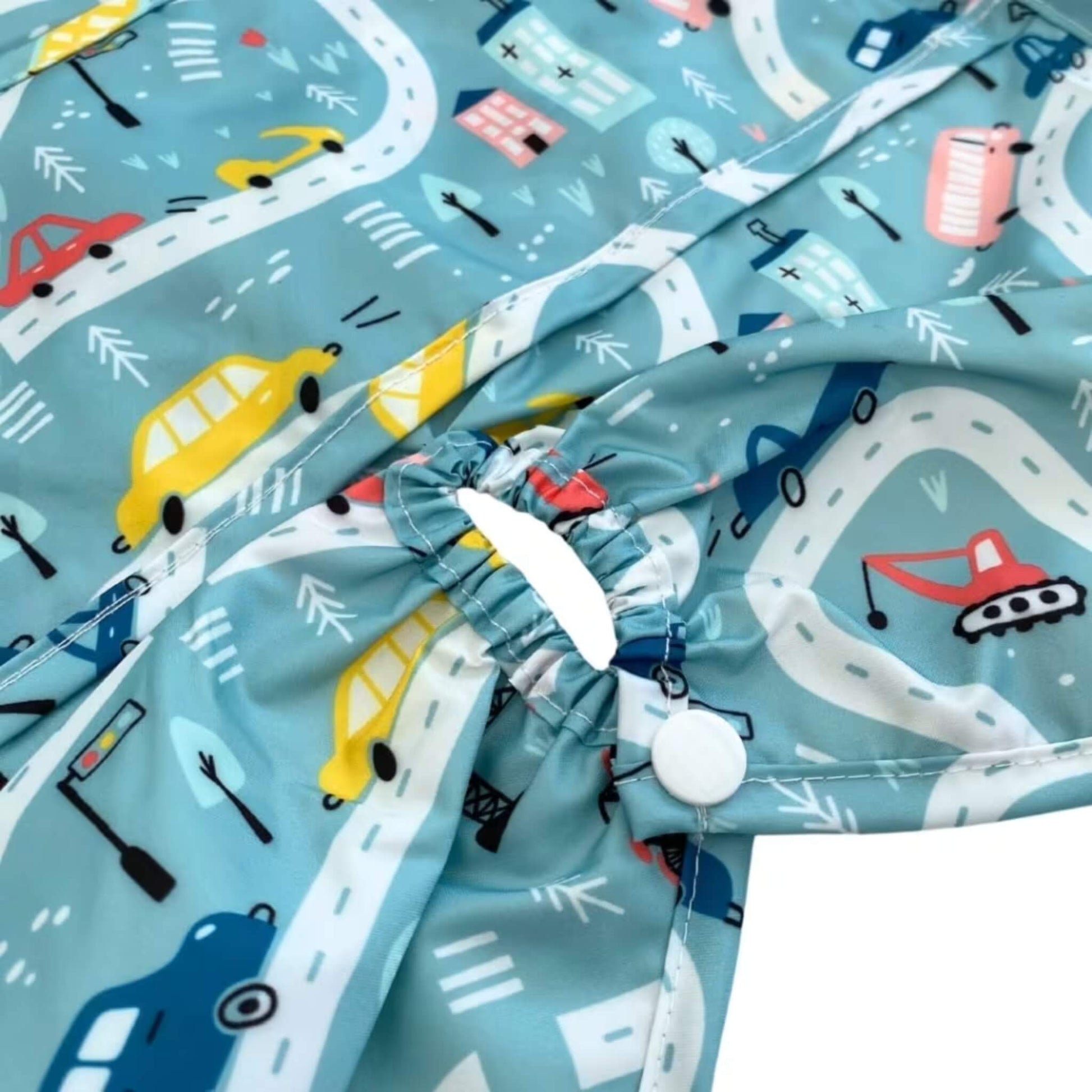 Close-up of a long sleeve highchair bib showing an elasticated highchair attachment opening with popper fastening and gathered wipe-clean fabric in the Roadmap print.