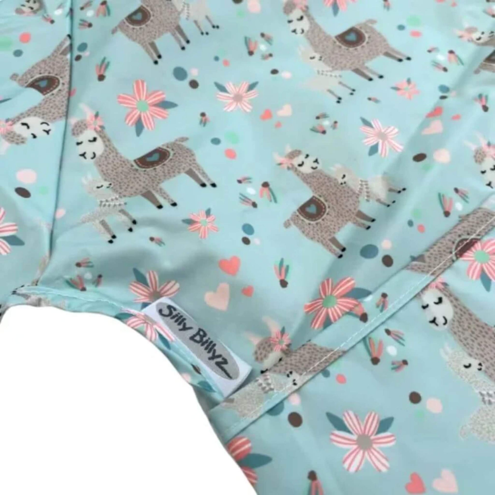 Close-up of wipe-clean baby bib fabric showing Llama print with stitched edging and sewn-in brand label.