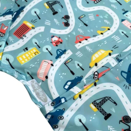 Close-up of wipe-clean baby bib fabric showing road, car and construction motifs with stitched edging and smooth coated surface.