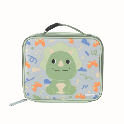 A rectangular kids lunch bag with a top handle, featuring a cute green cartoon dinosaur on a light blue background with colourful retro game controller and confetti patterns. The brand name 'SKIP HOP' is visible on a small tag near the bottom right.