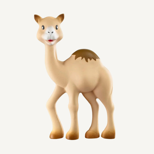 A natural rubber camel-shaped baby teething toy standing upright, with a smooth beige body, long legs, and a friendly illustrated face.