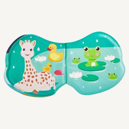 Open bath book page featuring Sophie la Girafe sitting beside ducks and frogs on lily pads in a pond scene with raindrops.