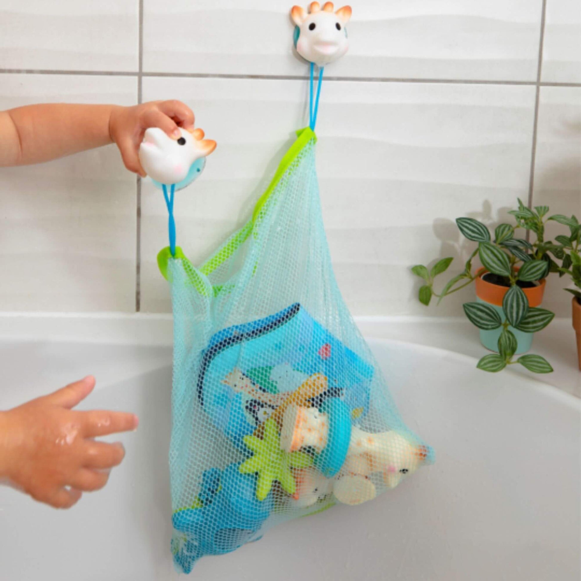 A Bath toy storage net holding toys, attached to tiled walls with suction cups, keeping bath time tidy and organised.