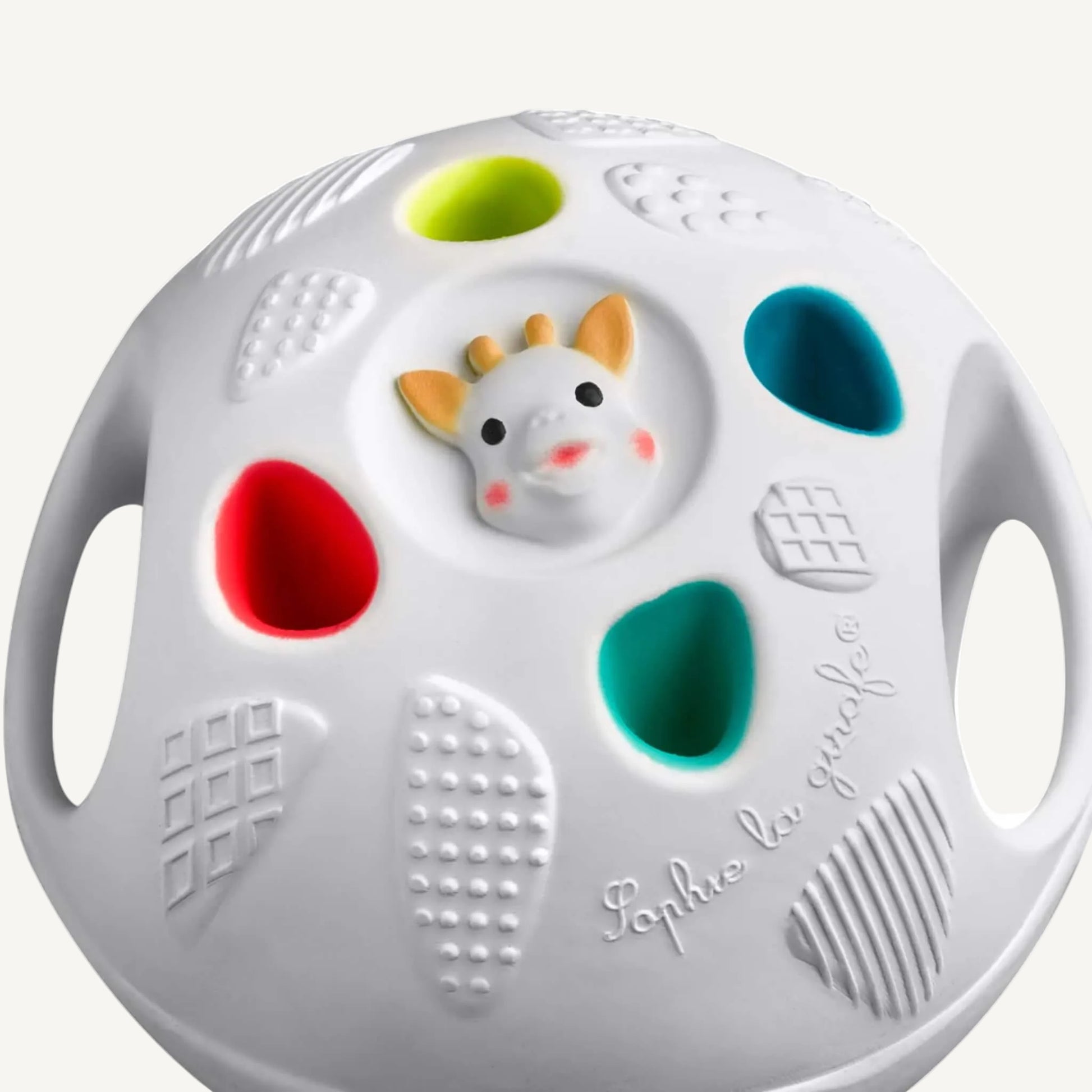 Angled view of a white sensory ball showing varied raised textures, coloured insets, and integrated hand holes for gripping.